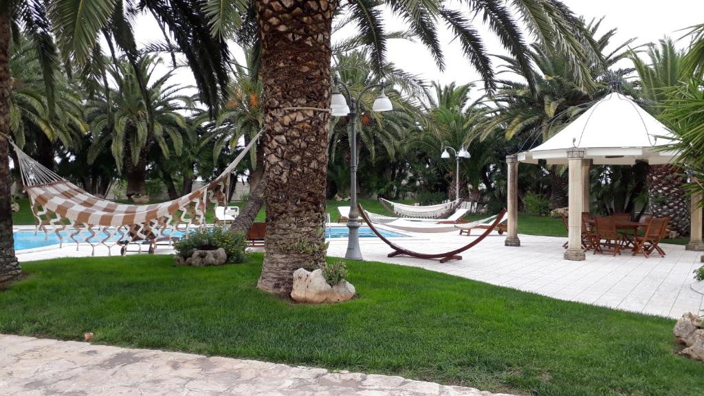 un complexe avec des hamacs et une piscine bordée de palmiers dans l'établissement Villa Incoronata, à Nardò