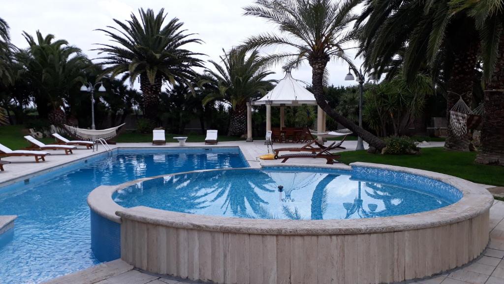une grande piscine avec des chaises et un gazebo dans l'établissement Villa Incoronata, à Nardò