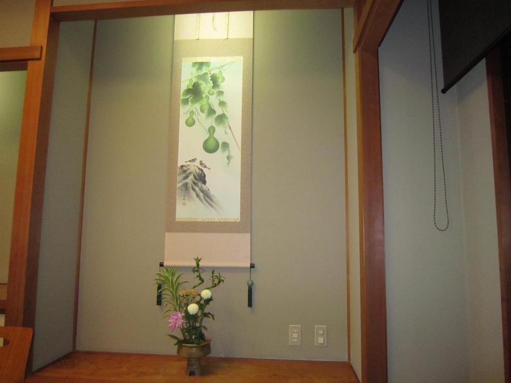 un couloir avec une porte ornée d'un vase de fleurs dans l'établissement Hotel Spax Kusatsu, à Kusatsu