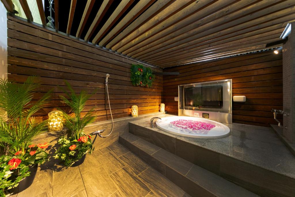 La salle de bains est pourvue d'une baignoire, d'une télévision et de fleurs. dans l'établissement i RESORT ARTIA Luxury Gifu (Adult Only), à Gifu
