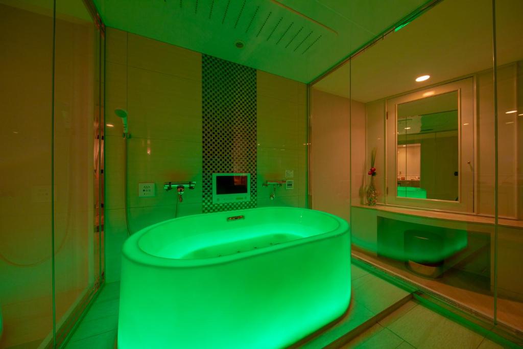 La salle de bains est pourvue d'une baignoire verte et d'une fenêtre. dans l'établissement Hotel Eldia Yamanashi (Adult Only), à Fuefuki 52 autres photos
