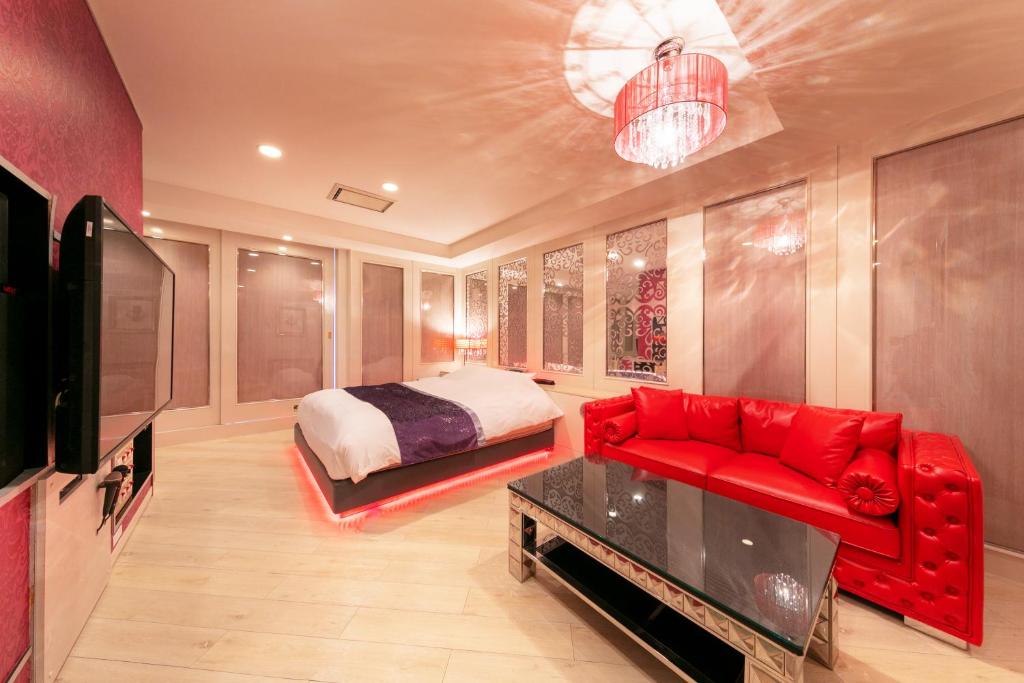 une chambre avec un lit et un canapé rouge dans l'établissement Hotel Eldia Yamanashi (Adult Only), à Fuefuki