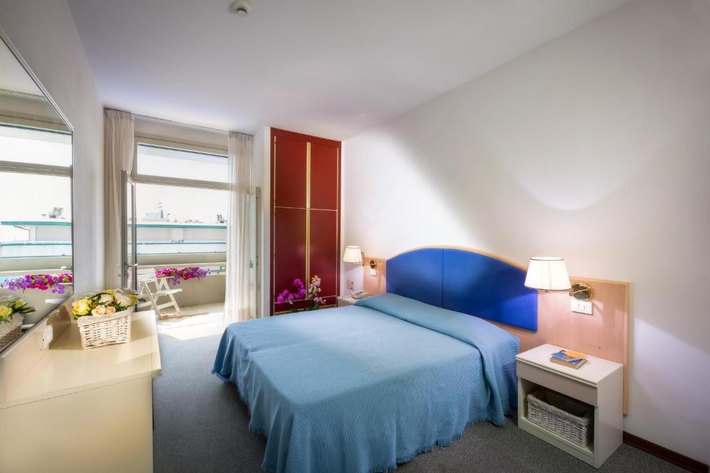 une chambre avec un lit bleu et un balcon dans l'établissement Hotel Metropol, à Caorle