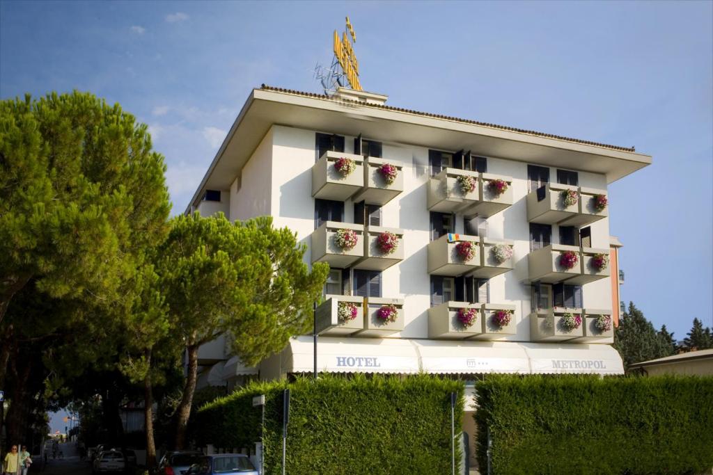 un immeuble d'appartements blanc avec des fleurs dans l'établissement Hotel Metropol, à Caorle