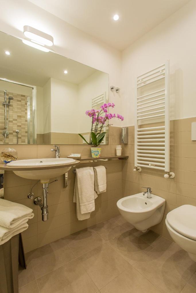 une salle de bain avec un lavabo, des toilettes et un miroir dans l'établissement Hotel Adelphi, à Riccione