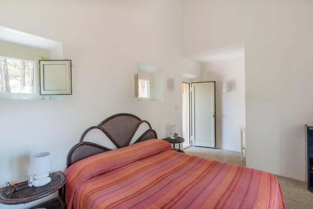 une chambre blanche avec un lit avec une couverture rayée dans l'établissement Villa Corallo, à Costa Paradiso