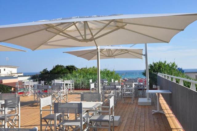 un patio avec des tables et des chaises sous des parasols blancs dans l'établissement Hotel Intervallo, à Torre Lapillo
