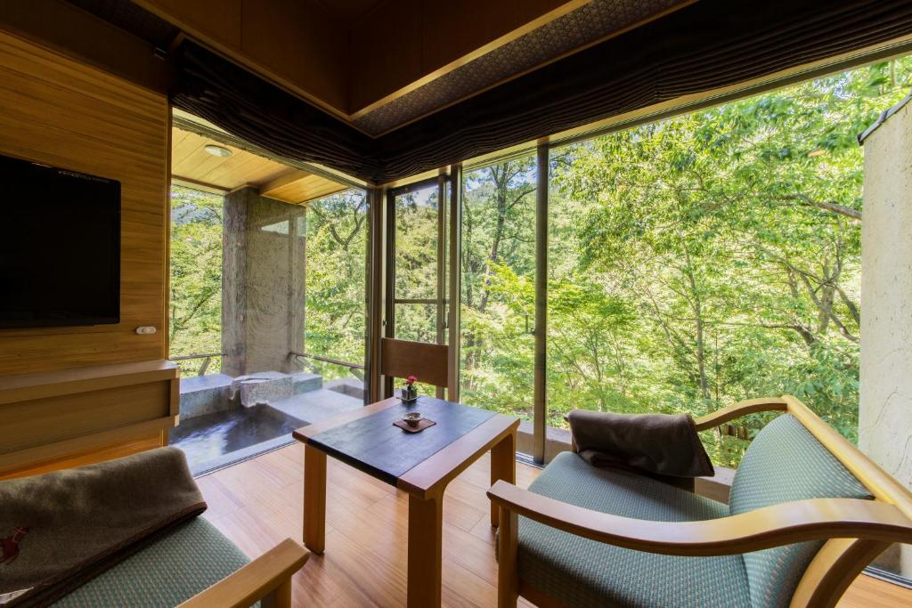- un salon avec une table, des chaises et une grande fenêtre dans l'établissement Bettei Senjyuan, à Minakami