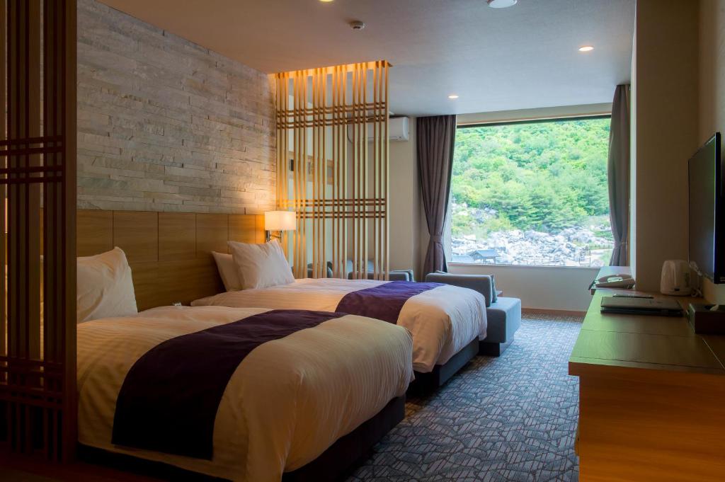 une chambre d'hôtel avec deux lits et une fenêtre dans l'établissement Unzen Kyushu Hotel, à Unzen