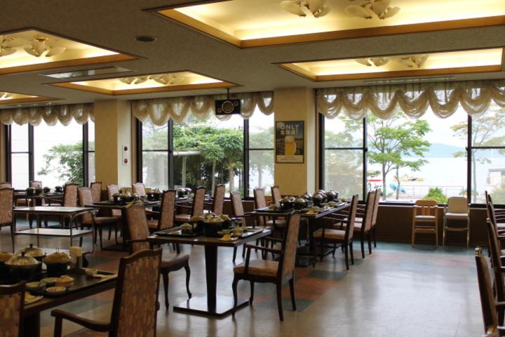 une salle à manger avec tables, chaises et fenêtres dans l'établissement Toya Kanko Hotel, à Lac Tōya