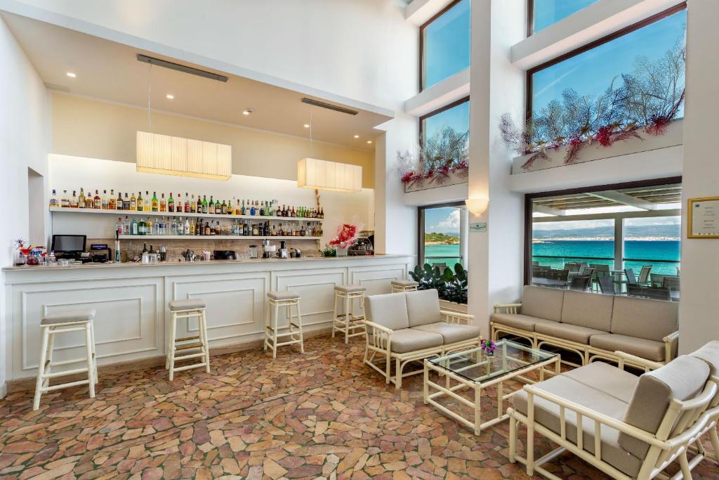 un restaurant avec un bar avec des chaises et des tables dans l'établissement Hotel Dei Pini, à Alghero