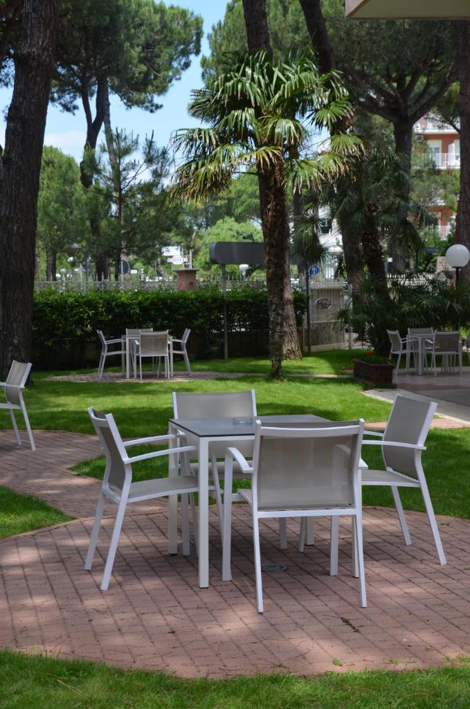 une table et des chaises dans un parc arboré dans l'établissement Hotel Rosen Garden, à Milano Marittima
