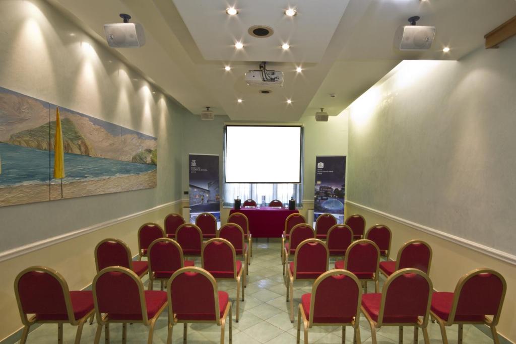 une salle de conférence avec des chaises rouges et un écran dans l'établissement Hotel Regina Palace Terme, à Ischia
