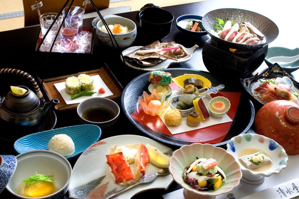une table avec de nombreuses assiettes de nourriture dessus dans l'établissement Oyado Kiyomizuya, à Noboribetsu