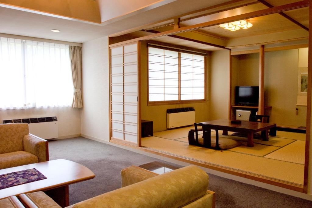 un salon avec une table et une télévision dans l'établissement Oyado Kiyomizuya, à Noboribetsu