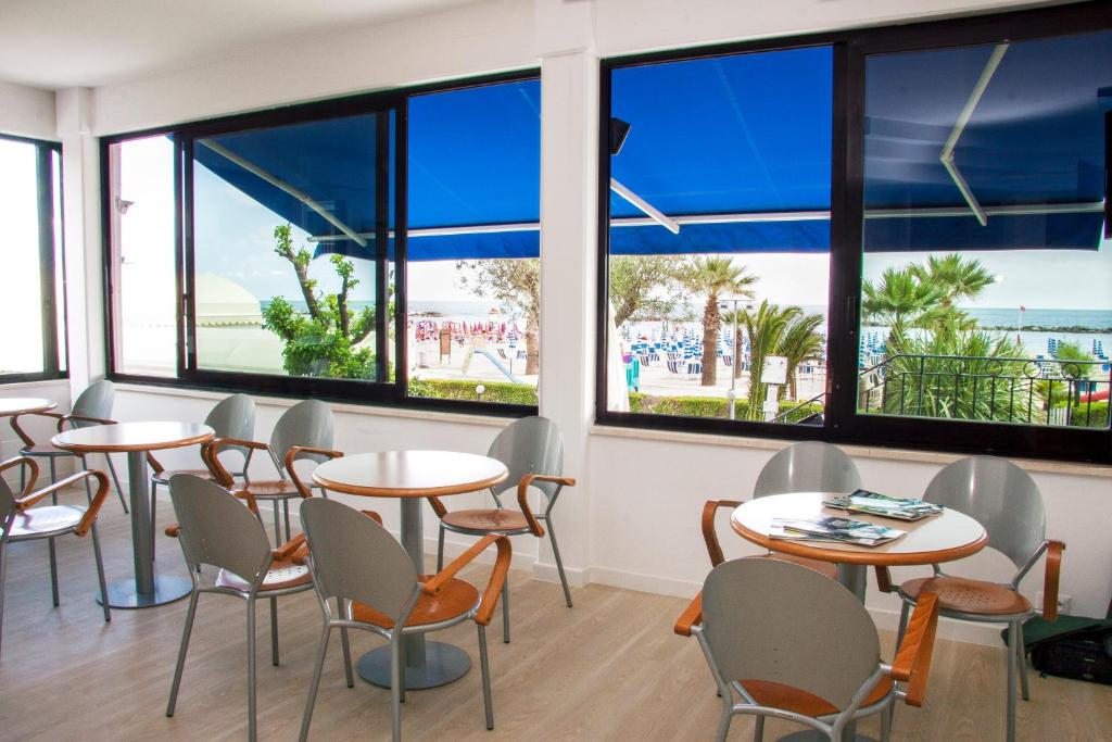 un restaurant avec des tables et des chaises et de grandes fenêtres dans l'établissement Residence Sunrise, à San Benedetto del Tronto