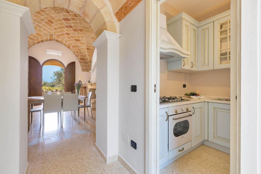 une cuisine avec des placards blancs et une salle à manger dans l'établissement Villa Satis by Perle di Puglia, à Casarano