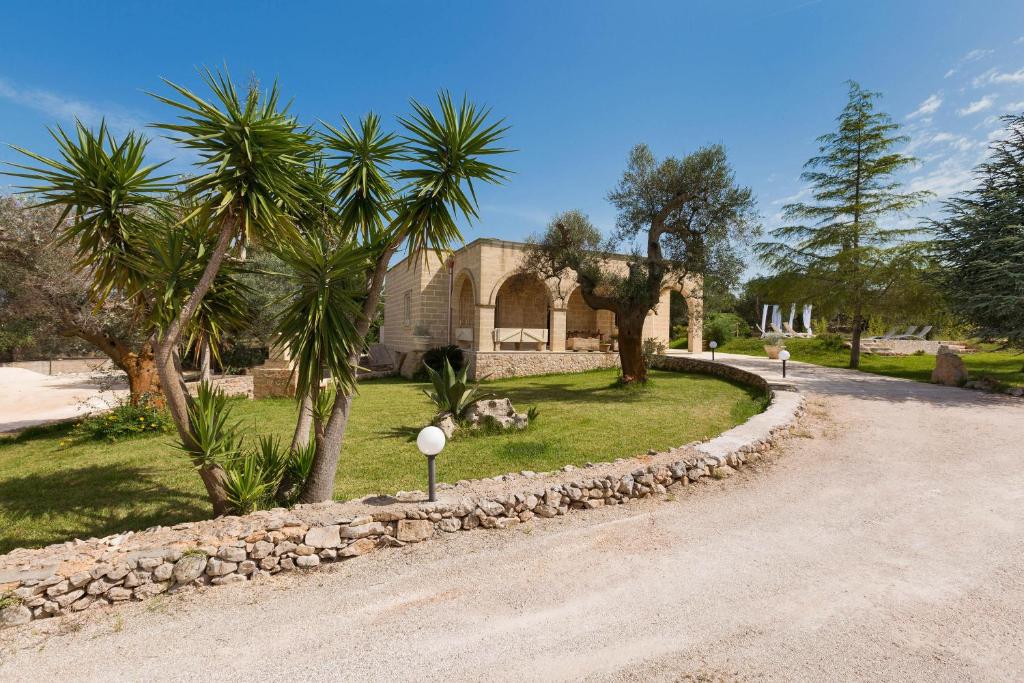 une maison avec des palmiers et une route en gravier dans l'établissement Villa Satis by Perle di Puglia, à Casarano