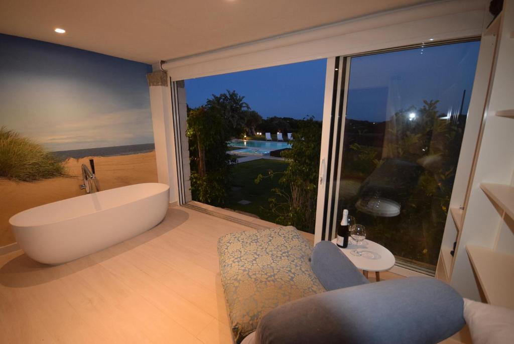 une salle de bain avec baignoire et une grande fenêtre dans l'établissement VILLA BAIRES - CHIA, à Domus de Maria
