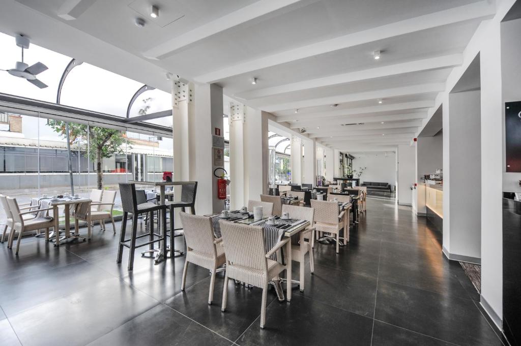 une salle à manger avec des tables et des chaises dans un restaurant dans l'établissement Bellini Relais, à Lignano Sabbiadoro