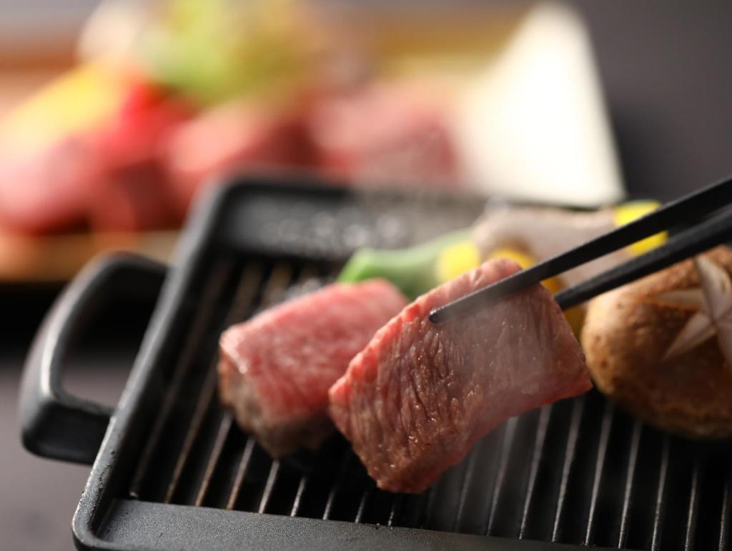 un groupe de viandes sur un grill avec pinces dans l'établissement Yoshinotei, à Iida