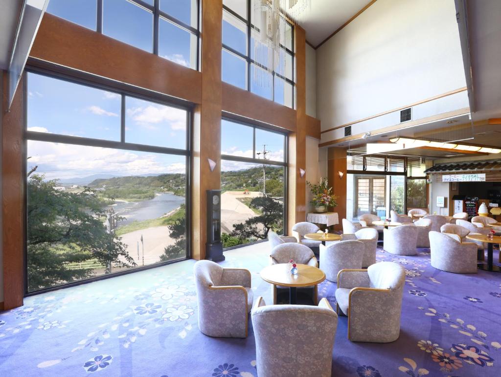 - un hall avec des chaises, des tables et de grandes fenêtres dans l'établissement Yoshinotei, à Iida
