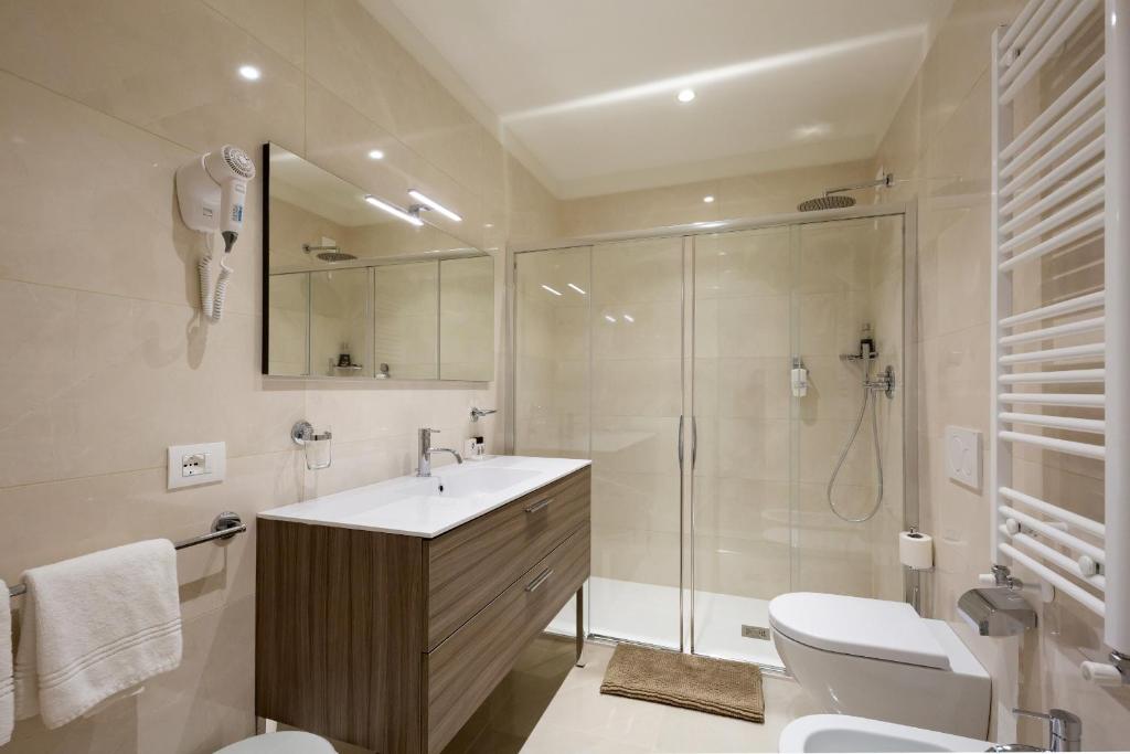 une salle de bain avec douche, lavabo et toilettes dans l'établissement International Beach Hotel, à Caorle