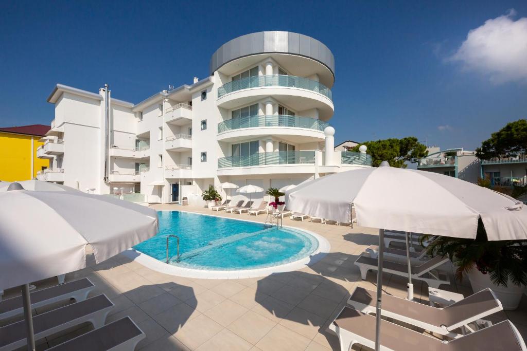 un grand bâtiment avec une piscine et deux parasols dans l'établissement International Beach Hotel, à Caorle