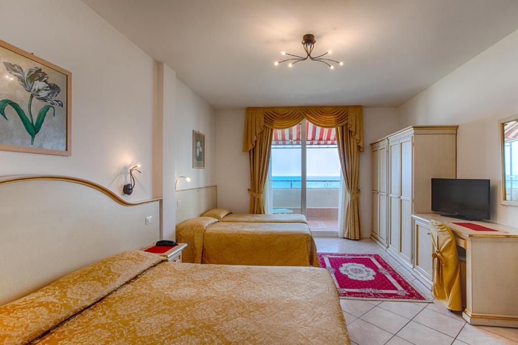 une chambre d'hôtel avec deux lits et une télévision dans l'établissement Hotel Elpiro, à Lido di Jesolo
