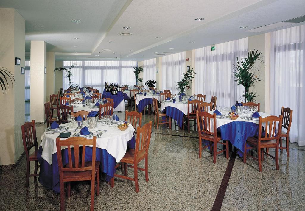 une salle à manger avec tables et chaises avec nappe bleue dans l'établissement Hotel San Gaetano, à Grisolia