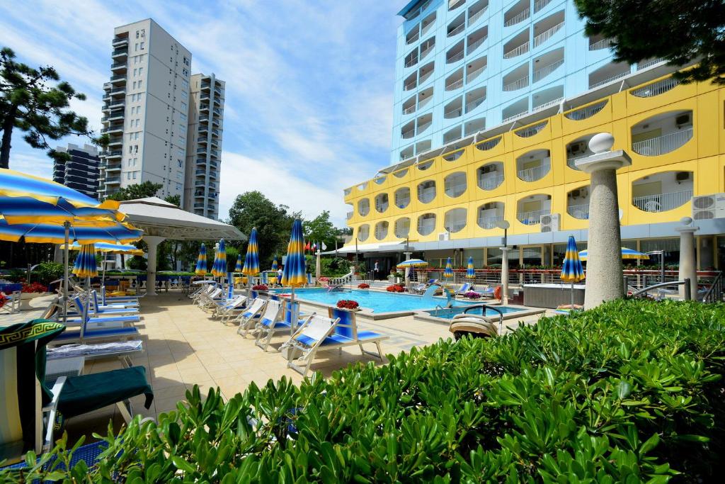 une piscine avec chaises et parasols et un hôtel dans l'établissement Hotel Colorado, à Lignano Sabbiadoro