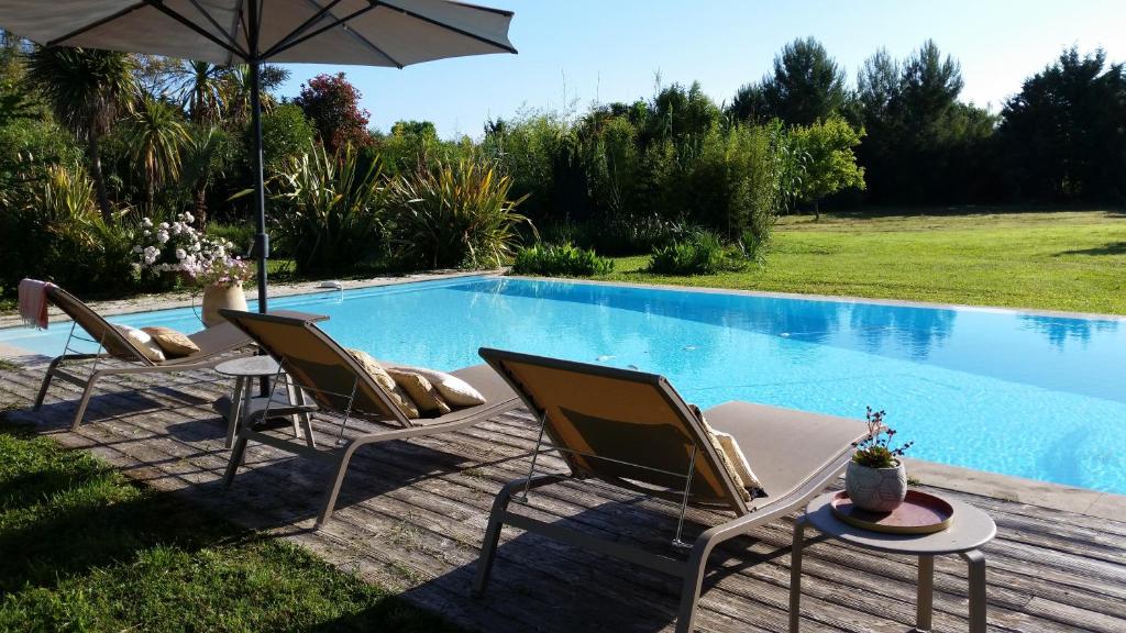 deux chaises et un parasol à côté d'une piscine dans l'établissement Domaine Sesquier Mas d'exception Acacia, à Mèze 8 autres photos