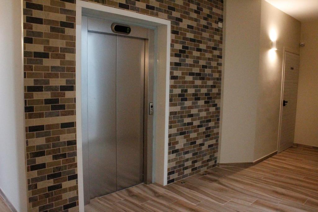 un couloir avec un mur en briques et une porte en verre dans l'établissement Hotel Royal - Beauty & Spa, à Porto Cesareo