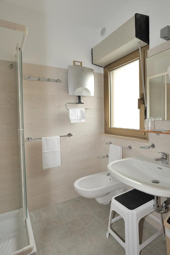 une salle de bain avec un lavabo et des toilettes et une fenêtre dans l'établissement Hotel Lidia, à Alba Adriatica