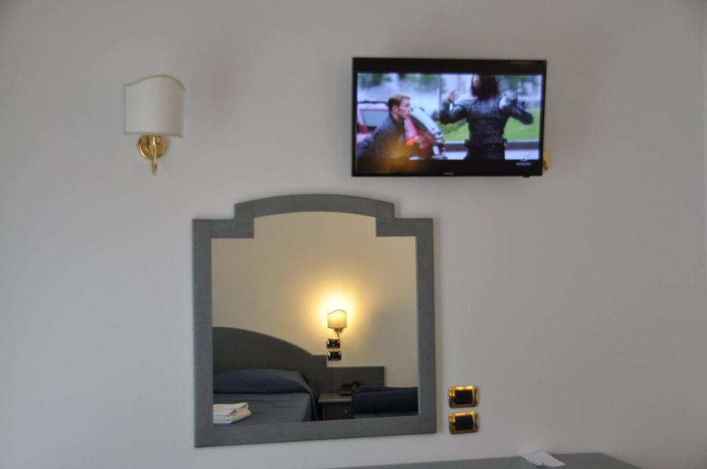 un miroir dans une pièce avec une télévision fixée au mur dans l'établissement Hotel Scoglio Del Leone, à Zambrone