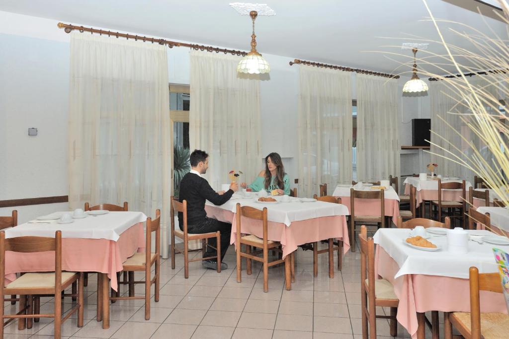 un homme et une femme assis à une table dans un restaurant dans l'établissement Hotel Lidia, à Alba Adriatica