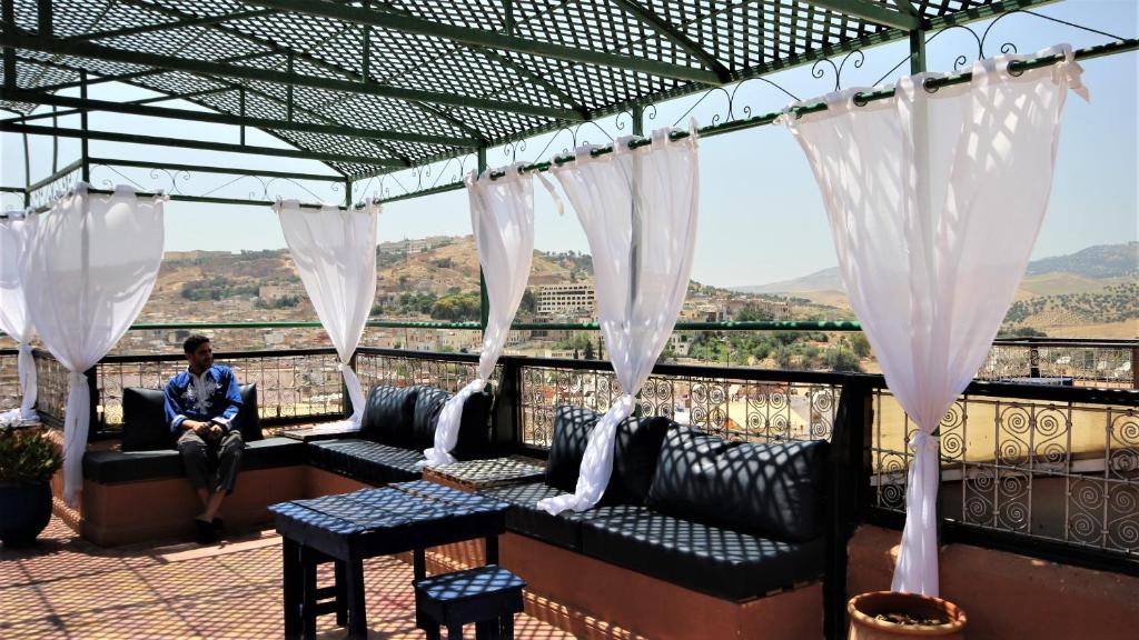 un homme assis sur un balcon avec des rideaux blancs dans l'établissement Riad Razane Fez, à Fès 28 autres photos