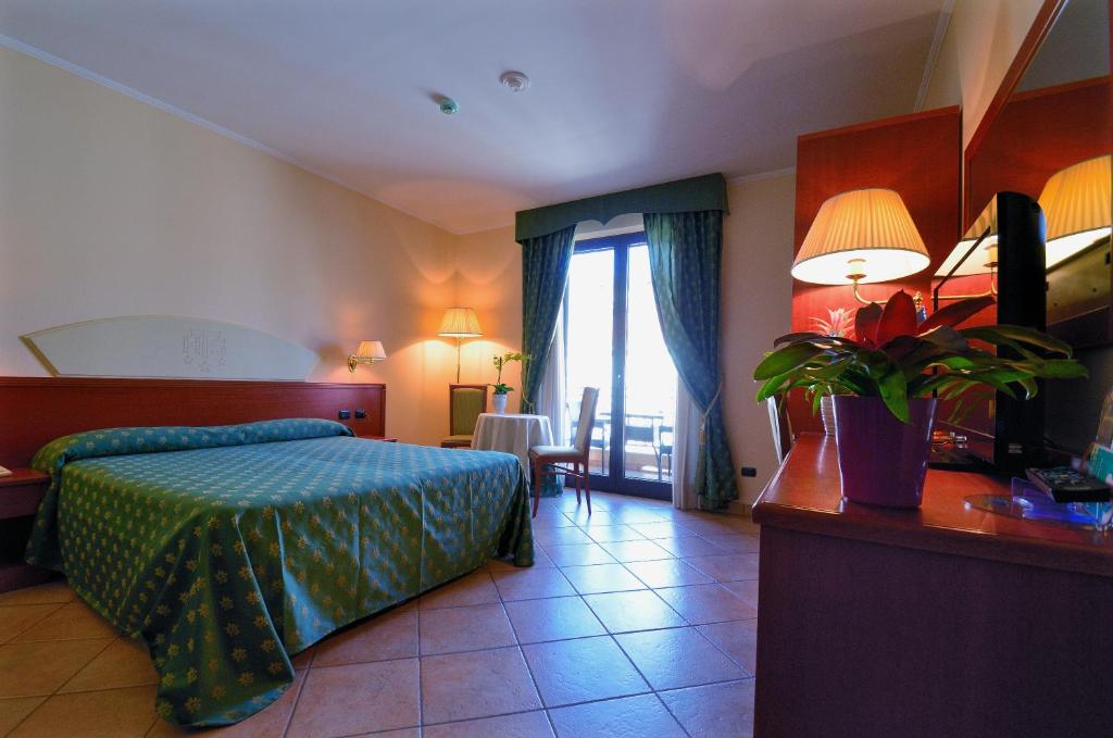 une chambre avec un lit et une table avec une plante dans l'établissement Hotel Tito Serrano', à Melito di Porto Salvo