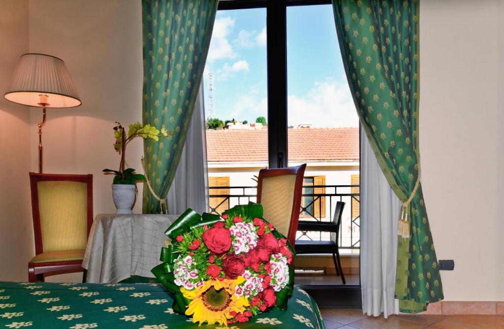 Cette chambre comprend un lit avec un bouquet de fleurs. dans l'établissement Hotel Tito Serrano', à Melito di Porto Salvo