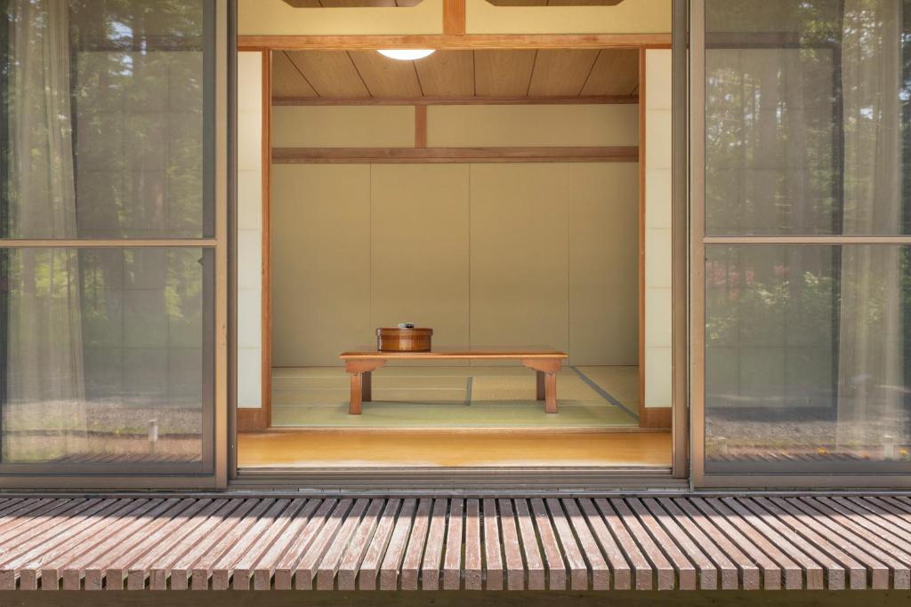 une table assise à l'intérieur d'une maison avec fenêtres dans l'établissement Yamanaka Lake Ryozan, à Yamanakako