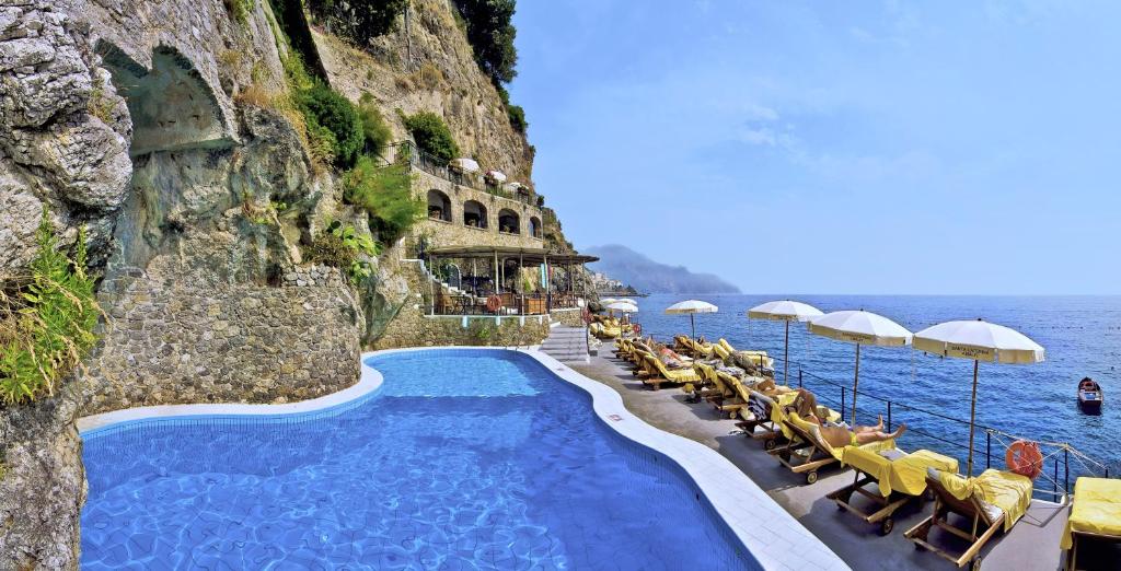 - une piscine au bord de l'océan avec des chaises et des parasols dans l'établissement Hotel Santa Caterina, à Amalfi