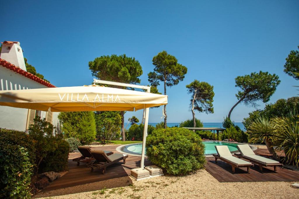un patio avec un parasol et des chaises et une piscine dans l'établissement Villa Alma - S4199, à Santa Margherita di Pula