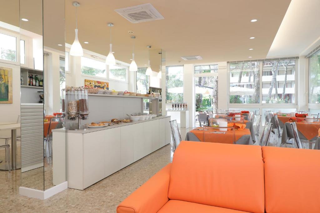 un restaurant avec des meubles orange, des tables et des fenêtres dans l'établissement Hotel Meublè Zenith, à Lignano Sabbiadoro