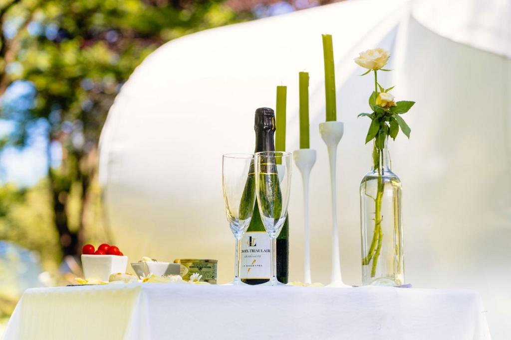 - une table avec une bouteille de vin et deux vases dans l'établissement Somn'en Bulle, à Najac