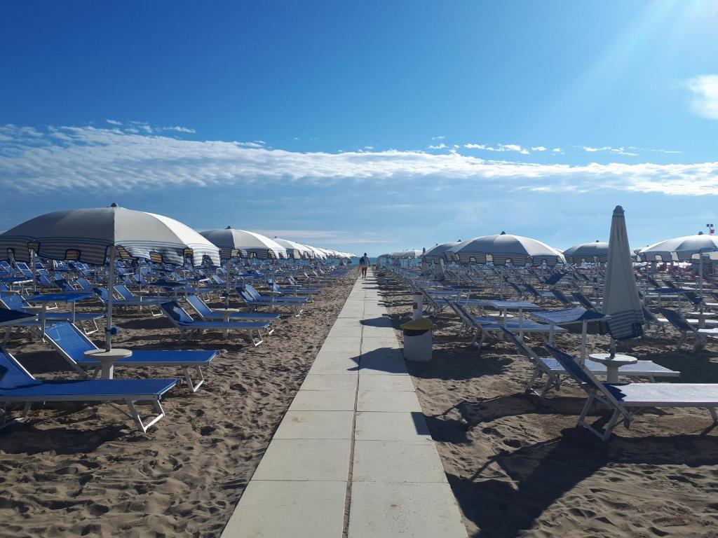 une plage avec des chaises et des parasols sur le sable dans l'établissement Residence Désirée, à Rimini