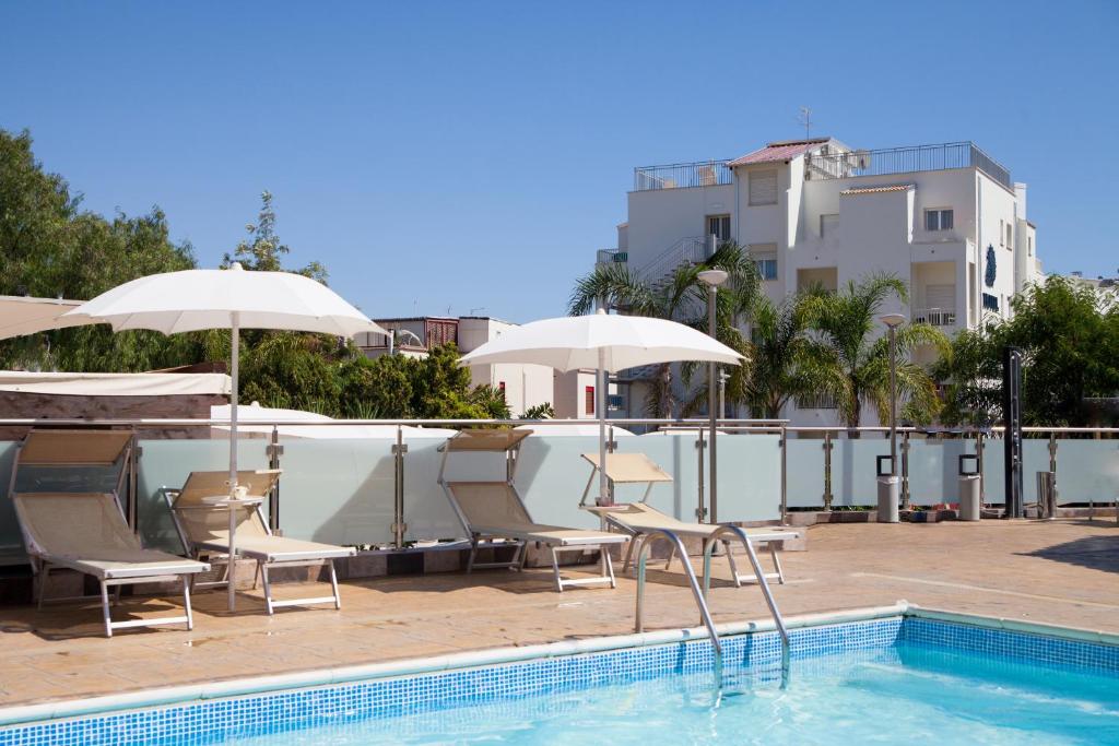 - une piscine avec des chaises et des parasols à côté d'un bâtiment dans l'établissement Hotel Costazzurra Museum & Spa, à San Leone