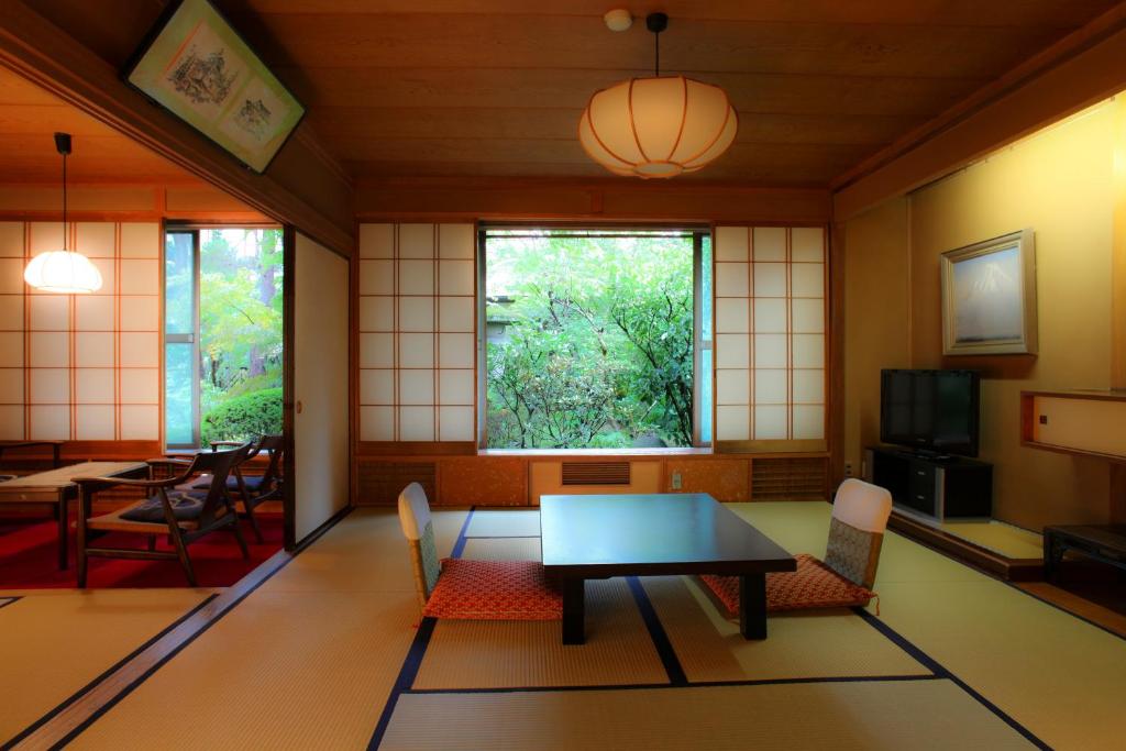 une pièce avec une table, des chaises et une fenêtre dans l'établissement Yudanaka Yumoto, à Yamanouchi