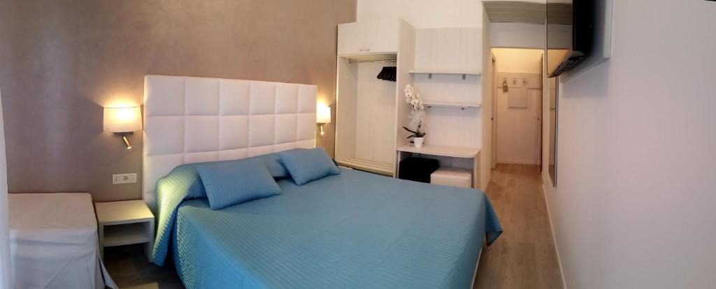 - une chambre avec un lit bleu et une salle de bains dans l'établissement Hotel Acapulco, à Lignano Sabbiadoro