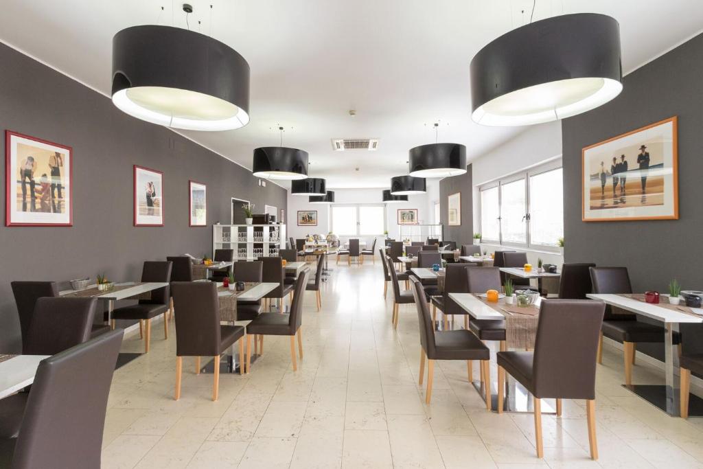 une salle à manger avec des tables, des chaises et des lumières dans l'établissement Hotel Aurora, à Lignano Sabbiadoro