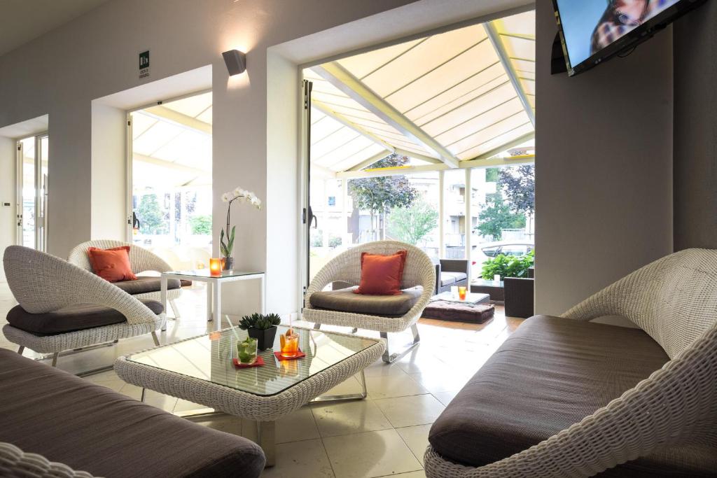 un salon avec des chaises, une table et des fenêtres dans l'établissement Hotel Aurora, à Lignano Sabbiadoro